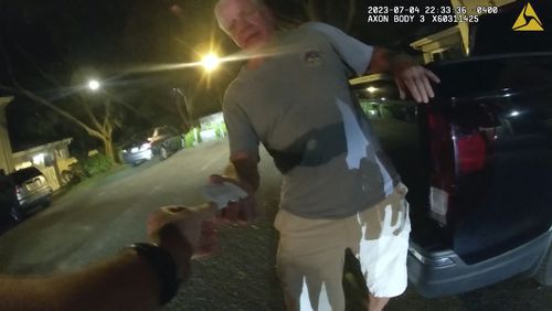 FILE - In this image from video provided by the Tampa Police Department, Joseph Ruddy, a prosecutor with the U.S. Attorney's Office in Tampa, hands his business card to Officer Taylor Grant, outside his home in Temple Terrace, Fla., on the evening of July 4, 2023. (Officer Taylor Grant/Tampa Police Department, File)