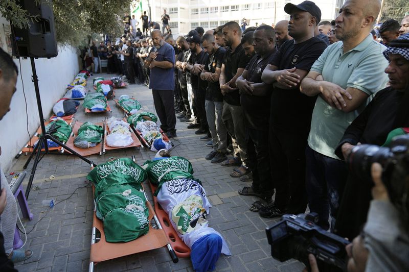 Mourners pray by the bodies of 18 Palestinians who were killed in an Israeli airstrike during their funeral in Tulkarem, Friday, Oct. 4, 2024. (AP Photo/Nasser Nasser)