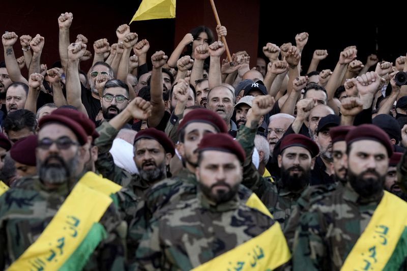 Mourners rise their hands and chant slogans during the funeral procession of Hezbollah fighters who were killed in Friday's Israeli strike, in the southern suburb of Beirut, Lebanon, Saturday, Sept. 21, 2024. (AP Photo/Bilal Hussein)