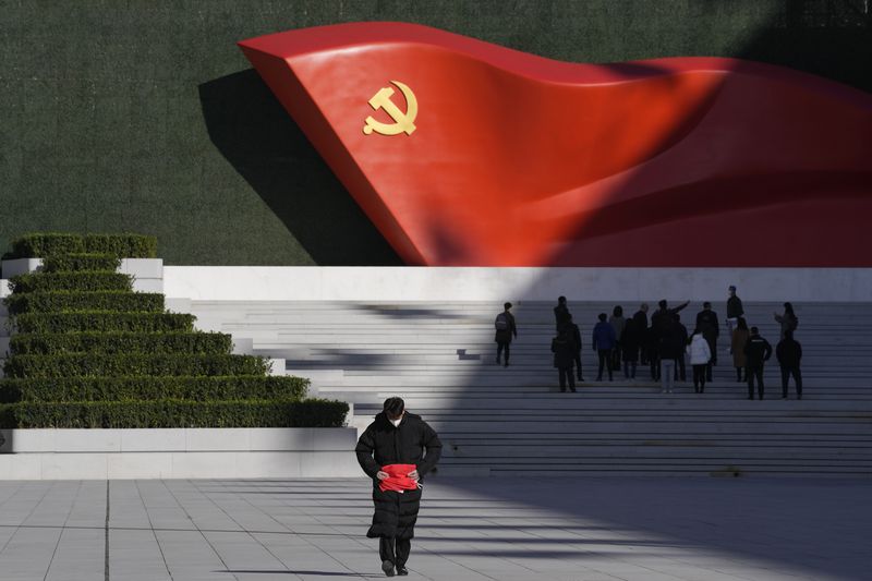 FILE - A worker folds a flag near a giant sculpture of the Chinese Communist Party flag outside the Museum of the Communist Party of China, in Beijing, Nov. 12, 2021. (AP Photo/Ng Han Guan, File)