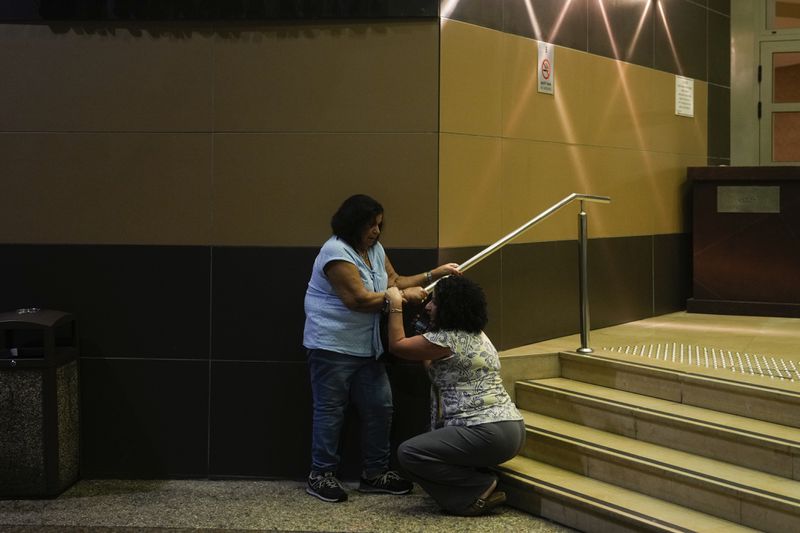 People take cover as a siren sounds a warning of incoming rockets fired from Lebanon, in Haifa, northern Israel, Monday, Sept. 23, 2024. (AP Photo/Ohad Zwigenberg)