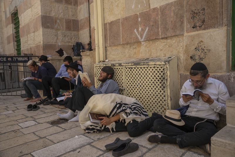 Ultra-orthodox Jewish man pray as they gather for the mourning ritual of Tisha B'Avn, in the Old City of Jerusalem , Tuesday, Aug. 13, 2024 . The Jewish holy day of Tisha B'Av, when Jews mourn the destruction of the biblical temples is marked Tuesday . (AP Photo/Ohad Zwigenberg)