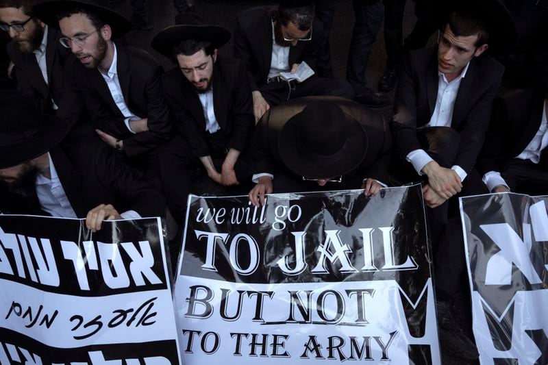 Ultra-Orthodox Jewish men block a highway as they take part in a protest against army recruitment in Bnei Brak, Israel, Thursday, June 27, 2024. Israel's Supreme Court unanimously ordered the government to begin drafting ultra-Orthodox Jewish men into the army, a landmark ruling seeking to end a system that has allowed them to avoid enlistment into compulsory military service. (AP Photo/Oded Balilty)