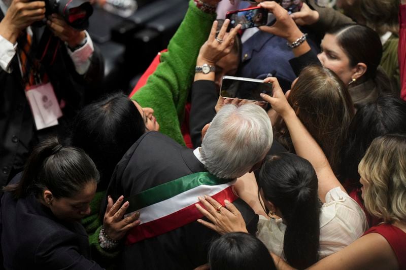 Outgoing President Andrés Manuel López Obrador poses for selfies upon his arrival at Congress for the swearing-in of Claudia Sheinbaum as Mexico's new president in Mexico City, Tuesday, Oct. 1, 2024. (AP Photo/Fernando Llano)