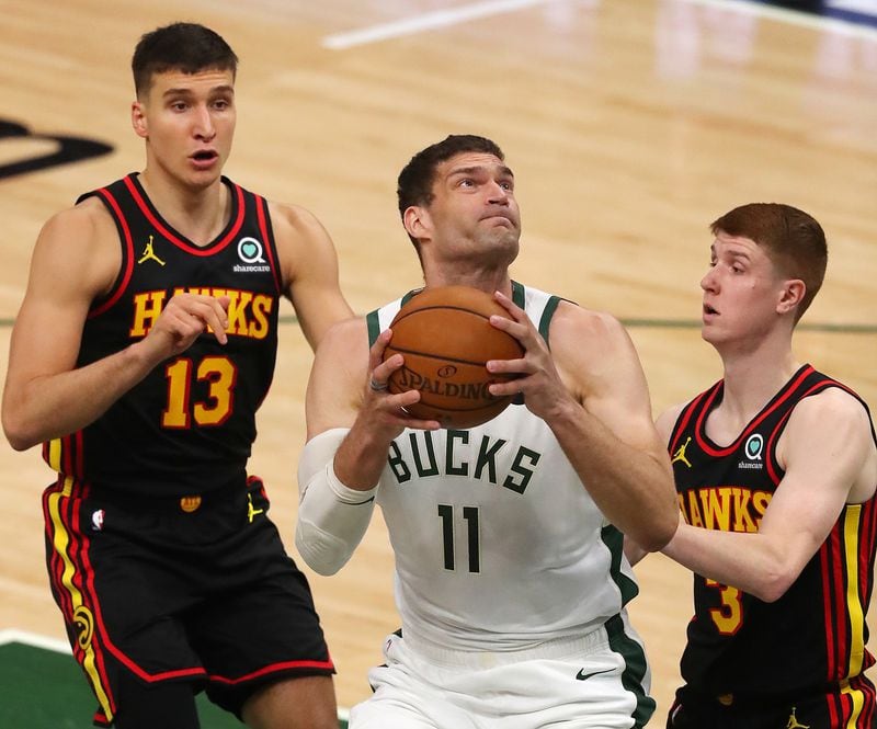 Hawks guards Bogdan Bogdanovic (left) and Kevin Huerter can't stop Milwaukee Bucks center Brook Lopez from going to the basket for two of his 33 points during the first quarter in game 5 of the NBA Eastern Conference Finals on Thursday, July 1, 2021, in Milwaukee.   “Curtis Compton / Curtis.Compton@ajc.com”