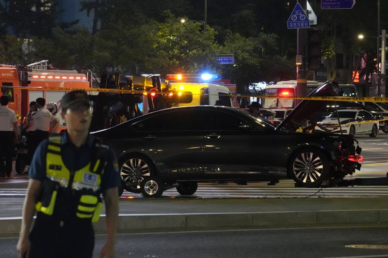 Police officers arrive at the scene of a car accident near Seoul City Hall in downtown Seoul, South Korea, Monday, July 1, 2024. A car hit pedestrians waiting at a traffic light in central Seoul on Monday evening, killing nine people and injuring four, South Korea's emergency officials said. (AP Photo/Ahn Young-joon)
