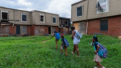 A family living in the Forest Cove Apartments walks to their home from the children's bus stop in August 2022. Atlanta completed the relocation of the condemned complex's residents in October of that year. (Arvin Temkar/The Atlanta Journal-Constitution/TNS)