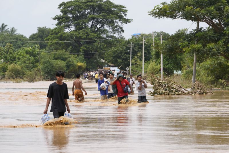 Local residents carrying food wade through a flooded road in Naypyitaw, Myanmar, Saturday, Sept. 14, 2024. (AP Photo/Aung Shine Oo)