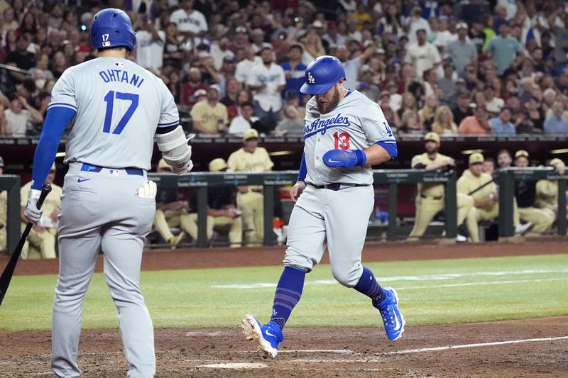 Los Angeles Dodgers' Max Muncy (13) scores a run on a wild pitch against the Arizona Diamondbacks as Dodgers' Shohei Ohtani (17), of Japan, looks on during the sixth inning of a baseball game Friday, Aug. 30, 2024, in Phoenix. (AP Photo/Ross D. Franklin)