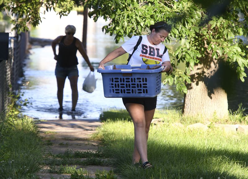 Missy Wheeler carries a basket while helping her mother-in-law Sheila Wheeler, back, evacuate her home on Whitcher Avenue, in Sioux City, Iowa's Riverside neighborhood Monday, June 24, 2024. Evacuations were occurring n the wake of flooding from the Big Sioux and Missouri Rivers. (Tim Hynds/Sioux City Journal via AP)
