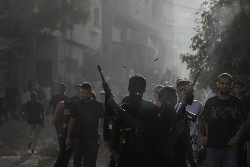 Gunmen fire their weapons during the funeral of three Palestinians killed by an Israeli airstrike in the occupied West Bank refugee camp of Tulkarem, Thursday, Aug. 22, 2024. The Palestinian Health Ministry says three people have been killed in an Israeli strike in the occupied West Bank. (AP Photo/Majdi Mohammed)