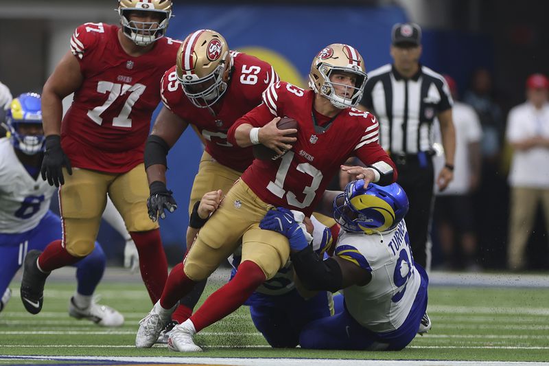 San Francisco 49ers quarterback Brock Purdy (13) is tackled by Los Angeles Rams defensive tackle Braden Fiske, bottom middle, and defensive tackle Kobie Turner, bottom right, during the second half of an NFL football game, Sunday, Sept. 22, 2024, in Inglewood, Calif. (AP Photo/Ryan Sun)