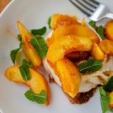 A mini peach jam-flavored pavlova topped with fresh peaches and zesty mint makes an elegant and easy summer dessert. (Virginia Willis for The Atlanta Journal-Constitution)
