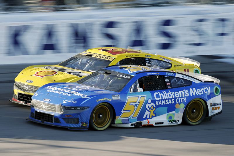 Corey LaJoie (51) and Joey Logano (22) race side-by-side as the head down the front straightaway during a NASCAR Cup Series auto race at Kansas Speedway in Kansas City, Kan., Sunday, Sept. 29, 2024. (AP Photo/Colin E. Braley)