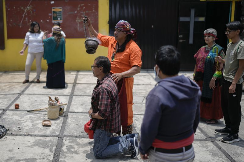 Residents and members of an Amaxac Indigenous organization use incense during a ceremony commemorating the 503 anniversary of the fall of the Aztec empire's capital, Tenochtitlan, in Mexico City, Friday, Aug. 9, 2024. (AP Photo/Eduardo Verdugo)