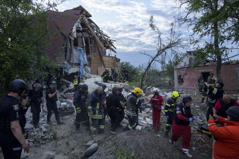 Rescue workers and police officers carry an injured person by a stretcher to an ambulance from a building which was destroyed by a Russian airstrike in Kharkiv, Ukraine, Monday, June 10, 2024. (AP Photo/Evgeniy Maloletka)