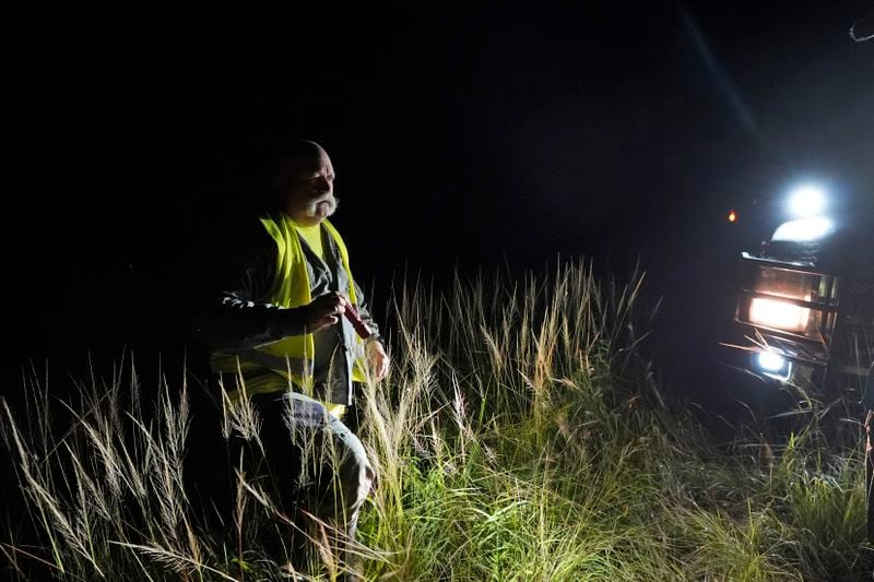 Thomas Aycock, a contractor with the Florida Fish and Wildlife Conservation Commission, heads back to his truck after checking out a marker along a levy as he searches for invasive Burmese pythons, Tuesday, Aug. 13, 2024, in the Florida Everglades. (AP Photo/Wilfredo Lee)