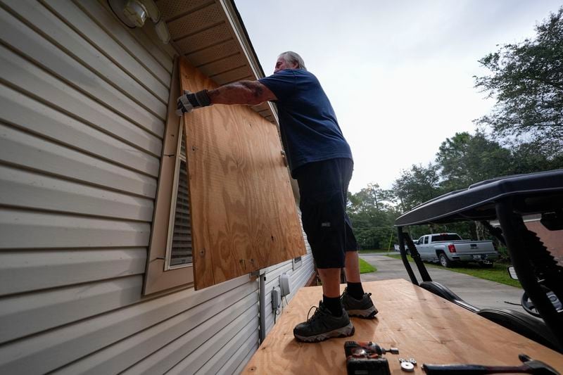 Dave McCurley boards up the windows to his home in advance of Tropical Storm Helene, expected to make landfall as a hurricane, in Ochlockonee Bay, Fla., Wednesday, Sept. 25, 2024. (AP Photo/Gerald Herbert)