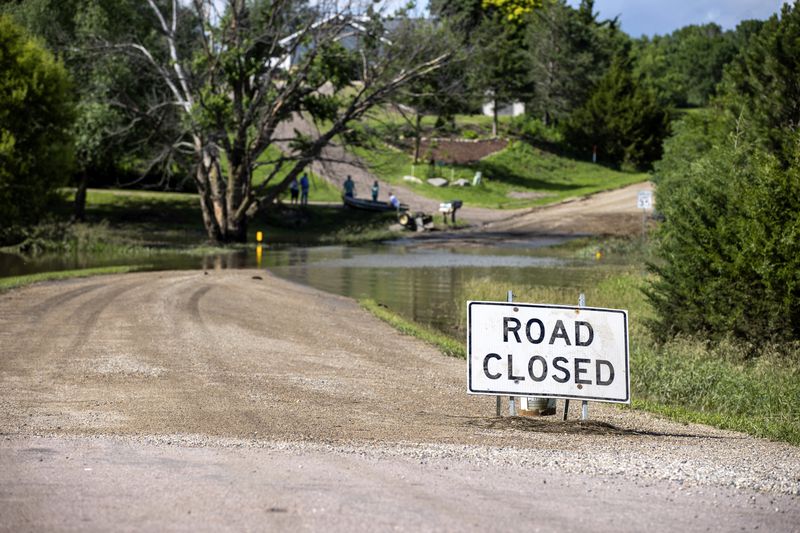 A road is closed off due to flooding caused by heavy rainfall, Saturday, June 22, 2024, in Lincoln County, S.D. (AP Photo/Josh Jurgens)