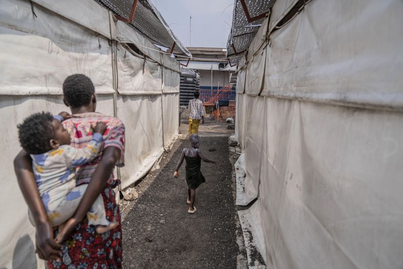 A girl suffering from a mpox walk past a treatment centre in Munigi, eastern Congo, Monday, Aug. 19, 2024. Congo will receive the first vaccine doses to address its mpox outbreak next week from the United States, the country's health minister said Monday, days after the World Health Organization declared mpox outbreaks in Africa a global emergency. (AP Photo/Moses Sawasawa)