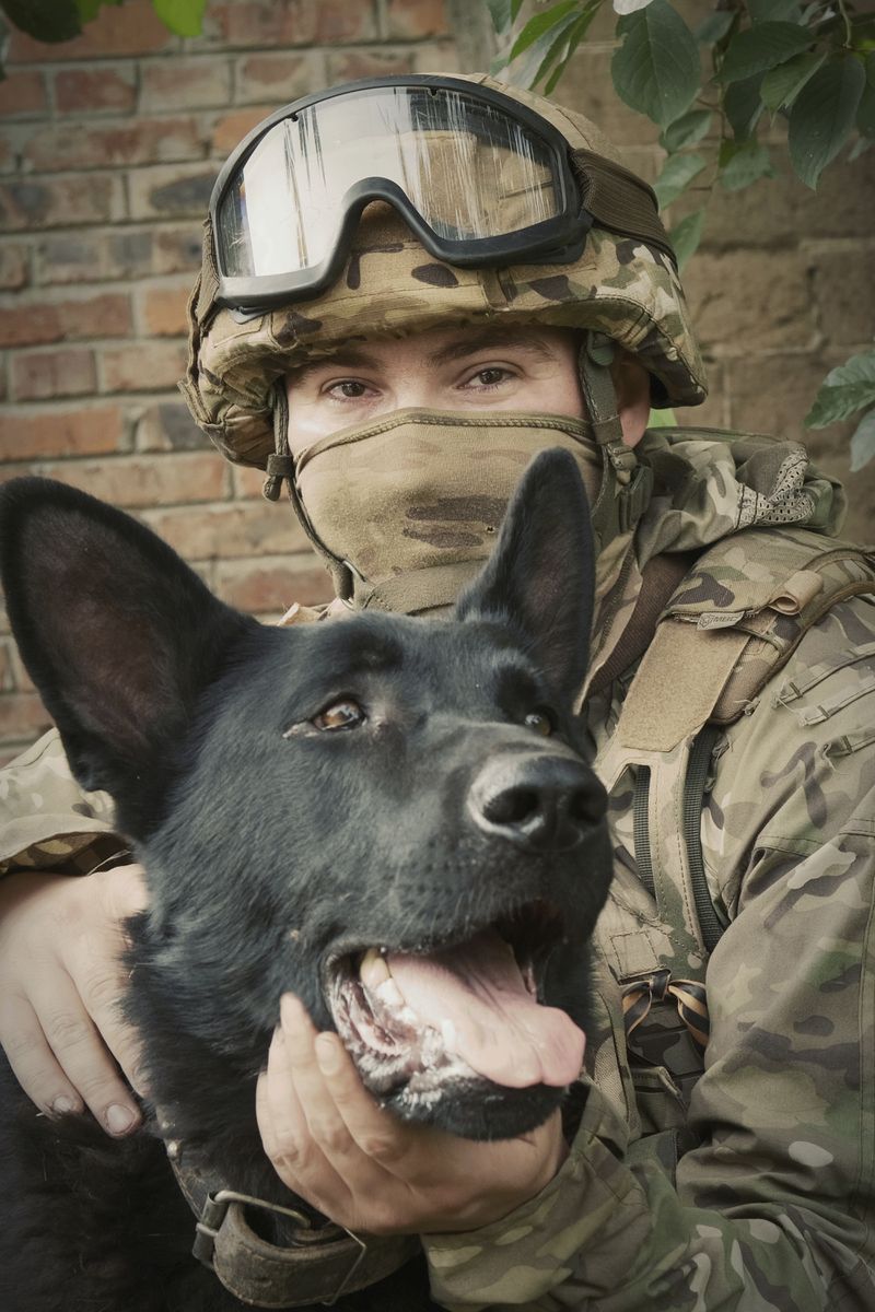In this photo released by the Russian Defense Ministry Press Service on Tuesday, June 25, 2024, a Russian soldier poses for photo with his dog in a shelter at a position in an undisclosed location in Ukraine. (Russian Defense Ministry Press Service via AP)