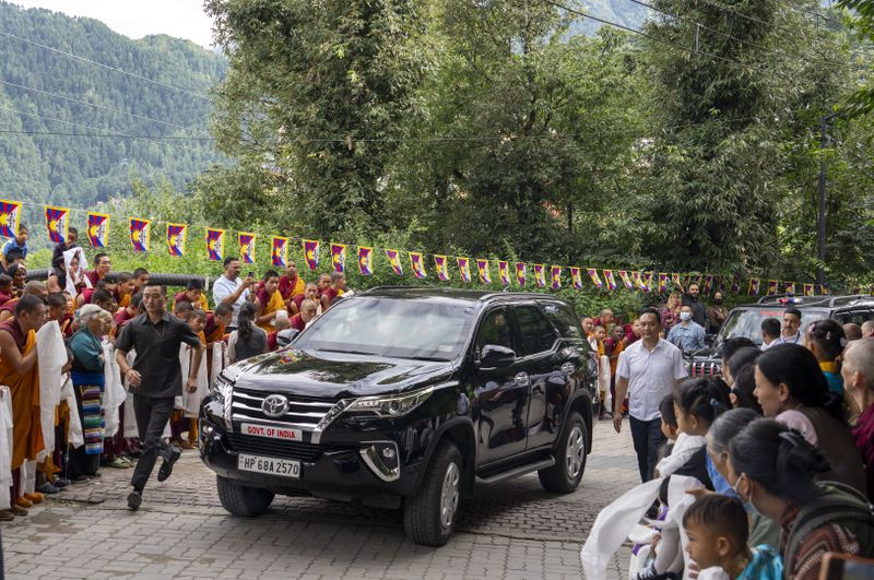 A security person runs along the vehicle in which Tibetan spiritual leader the Dalai Lama sits on his arrival in Dharamshala, India, Wednesday, Aug. 28, 2024. (AP Photo/Ashwini Bhatia)