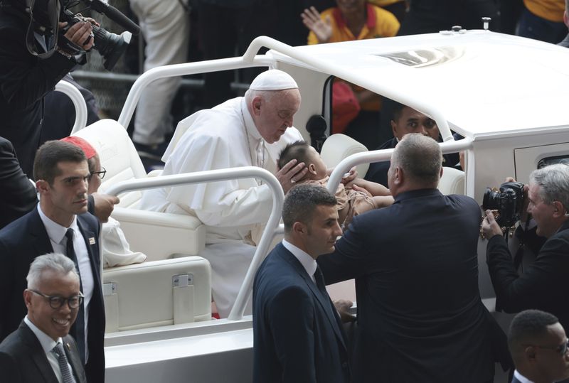 Pope Francis, center, blesses a child as he arrives for a holy Mass at a stadium in Jakarta, Thursday, Sept. 5, 2024. (Adi Weda/Pool Photo via AP)