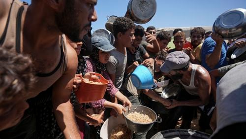 Displaced Palestinians gather for food distribution in Deir al Balah, central Gaza Strip, Friday, Aug. 23, 2024. (AP Photo/Abdel Kareem Hana)