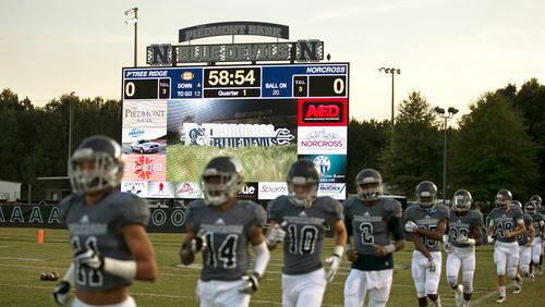 Norcross players jog onto the field in front of the school's Jumbotron before their game against Peachtree Ridge Friday at Norcross High School in Norcross, Ga., October 23, 2015. PHOTO / JASON GETZ