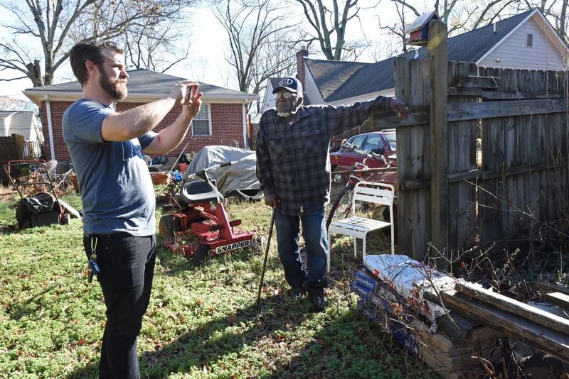 Justin Schaeffer (left) talks with Woodrow Williams in Williams' backyard where he needs additional repairs in Kirkwood. (Hyosub Shin / Hyosub.Shin@ajc.com)