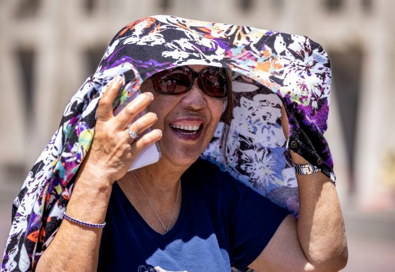 Lucita Corupuz, 80, visiting from St. Louis, covers up from the sun while visiting the University of Washington campus with family Sunday, July 7, 2024, in Seattle. An excessive heat warning — the National Weather Service's highest alert — was in effect for about 36 million people. (Ken Lambert/The Seattle Times via AP)
