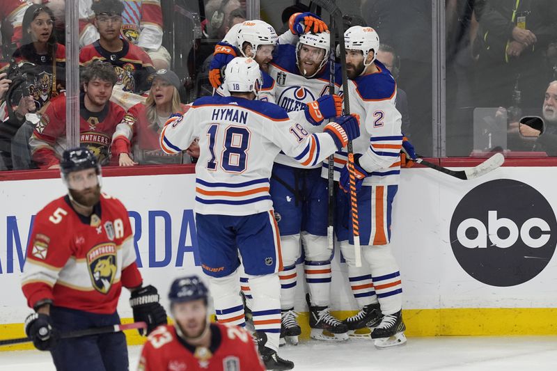 Edmonton Oilers center Connor McDavid (97), is congratulated by his teammates after scoring a goal during the second period of Game 5 of the NHL hockey Stanley Cup Finals against the Florida Panthers, Tuesday, June 18, 2024, in Sunrise, Fla. (AP Photo/Rebecca Blackwell)
