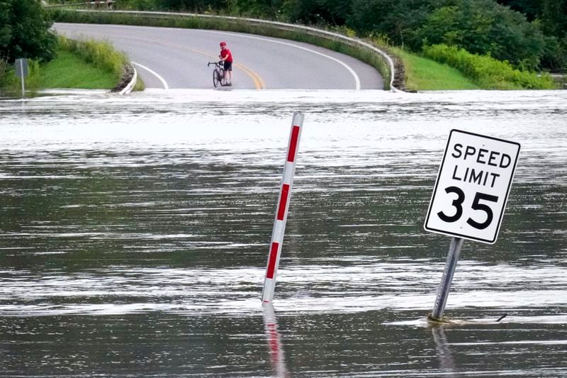 A cyclist pauses to look at the Winooski River, which overflowed its banks covering nearly a quarter mile of roadway, after remnants of Hurricane Beryl caused flooding, Thursday, July 11, 2024, in North Williston, Vt. (AP Photo/Charles Krupa)
