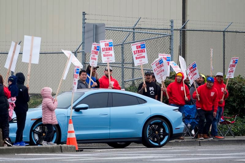 Boeing workers boo a car turning into the Everett factory parking lot as they wave picket signs while striking after union members voted to reject a contract offer, Sunday, Sept. 15, 2024, near the company's factory in Everett, Wash. (AP Photo/Lindsey Wasson)