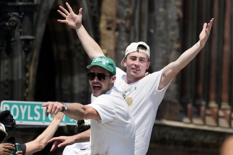 Boston Celtics' Payton Pritchard, right, celebrates the team's NBA basketball championship during a duck boat parade Friday, June 21, 2024, in Boston. (AP Photo/Michael Dwyer)