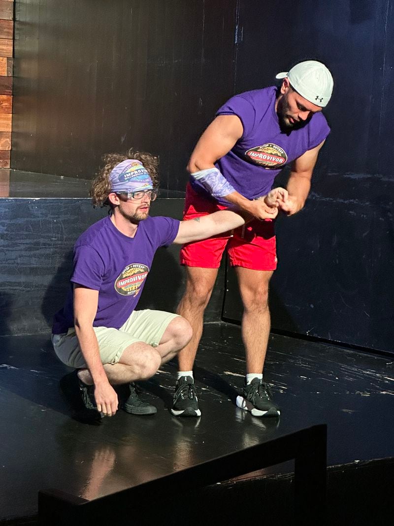 Noah Kitchens, playing shy Perry, gets his hands rubbed by Camilo Duarte, playing gym rat Ricardo during the second "Improvivor" show at Whole World Theatre August 10, 2024. RODNEY HO/rho@ajc.com