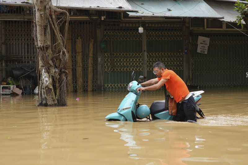 A man pushes his motorcycle in a flooded street in the aftermath of Typhoon Yagi, in Hanoi, Vietnam on Thursday, Sep. 12, 2024. (AP Photo/Hau Dinh)