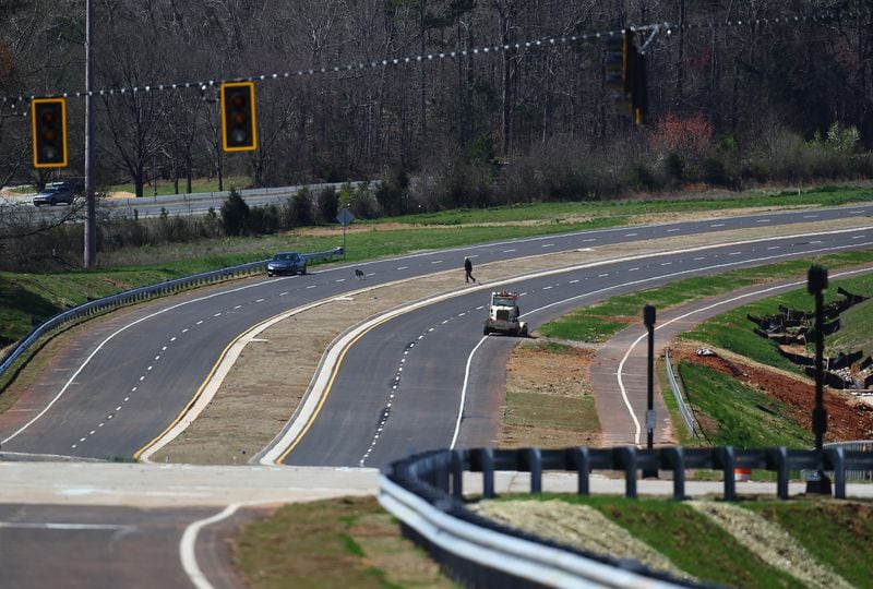 A man and his dog cross the four lane road near the intersection with Old Mill Road on the site of Rivian’s Georgia plant on Sunday, March 10, 2024, in Rutledge. Curtis Compton for The Atlanta Journal Constitution