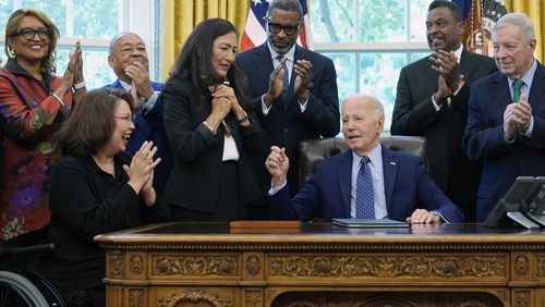 President Joe Biden, who is joined by civil rights leaders, community members, and elected officials, talks after handing Interior Secretary Deb Haaland, fourth from left, the pen he used to sign a proclamation in the Oval Office of the White House in Washington, Friday, Aug. 16, to designate the Springfield 1908 Race Riot National Monument. Sen. Tammy Duckworth, D-Ill., second from left, reacts. (AP Photo/Susan Walsh)