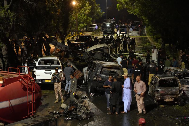 Security officials examine the site of an explosion that caused injures and destroyed vehicles outside Karachi airport, Pakistan, early Monday, Oct. 7, 2024. (AP Photo/Fareed Khan)