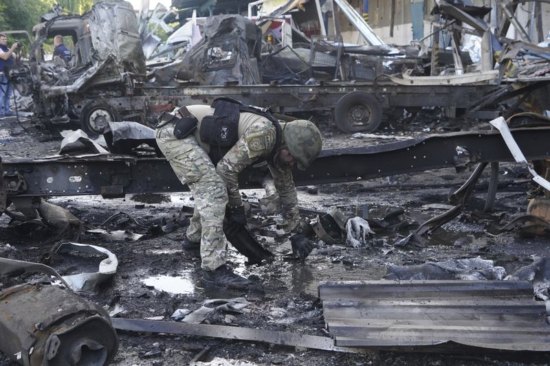 A police officer collects evidence after a Russian attack on Nova Poshta delivery in Kharkiv, Ukraine, Sunday, June 30, 2024. At least one person was killed and several injured. (AP Photo/Andrii Marienko)