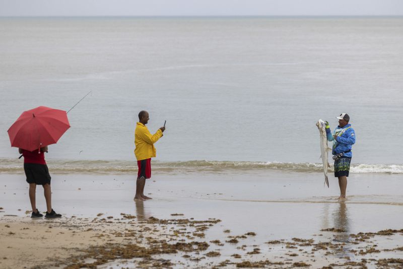 A man pose with a fish after Tropical Storm Ernesto passed through Rio Grande, Puerto Rico, Wednesday, Aug. 14, 2024. (AP Photo/Alejandro Granadillo)