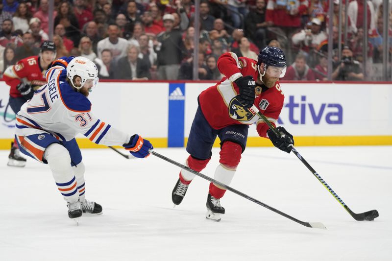 Florida Panthers center Sam Bennett (9) skates with the puck as Edmonton Oilers left wing Warren Foegele (37) defends during the second period of Game 5 of the NHL hockey Stanley Cup Finals, Tuesday, June 18, 2024, in Sunrise, Fla. (AP Photo/Wilfredo Lee)