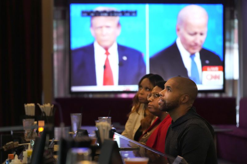 Tanzella Young, left, Crystal Blakley, center, and Jason Sanford watch the Presidential Debate at the M Lounge in the South Loop neighborhood of Chicago, Thursday, June 27, 2024. (AP Photo/Charles Rex Arbogast)