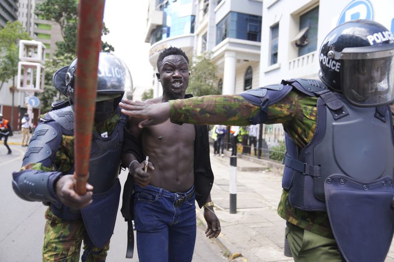 Kenyan riot police arrest a man during a protest over proposed tax hikes in a finance bill in downtown Nairobi, Kenya Tuesday, June. 25, 2024. (AP Photo/Brian Inganga)