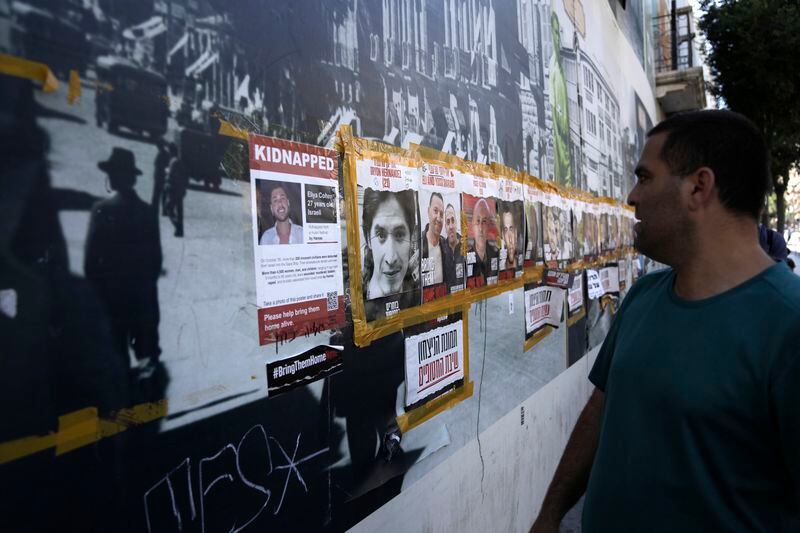A man looks at a poster of Oryon Hernandez Radoux, 30, second left, who was killed on Oct. 7, 2023, next to posters of hostages held by Hamas in the Gaza Strip, in central Jerusalem, Friday, May 24, 2024. The bodies of Michel Nisenbaum, 59, Hanan Yablonka, 42, and Oryon Hernandez Radoux, three hostages killed on Oct 7, were recovered overnight from Gaza, Israel's army said Friday May 24. (AP Photo/Mahmoud Illean)