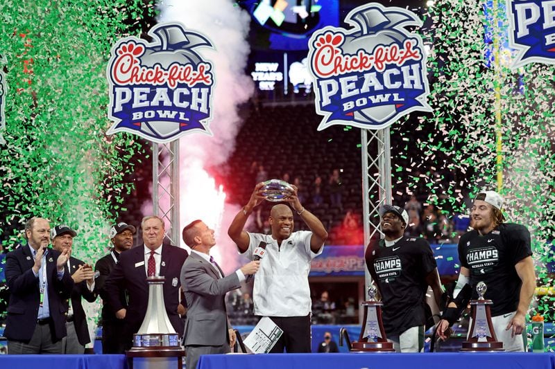 Michigan State Spartans head coach Mel Tucker hoists the trophy after their 31-21 win against the Pittsburgh Panthers during the Chick-fil-A Peach Bowl at Mercedes-Benz Stadium in Atlanta, Thursday, December 30, 2021. JASON GETZ FOR THE ATLANTA JOURNAL-CONSTITUTION



