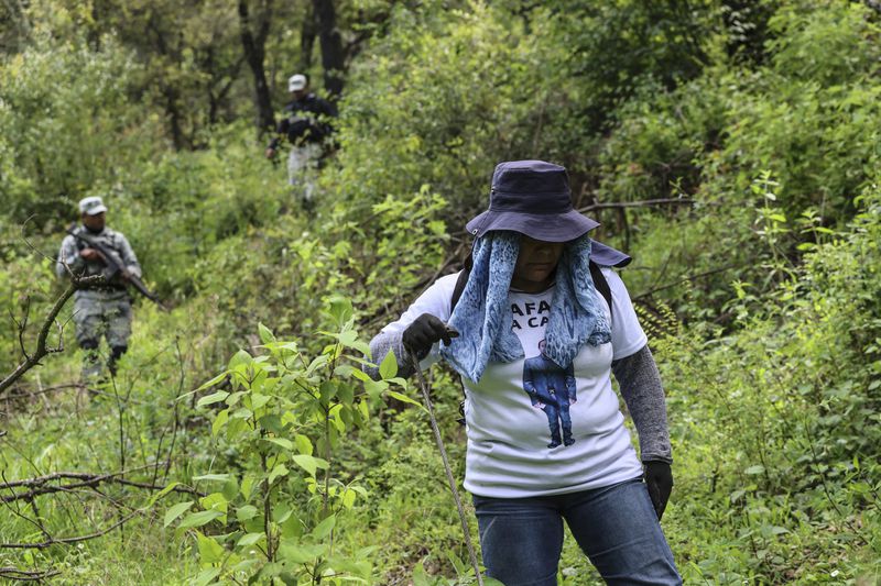 Angelica Montelongo, of the search collective "Uniendo Esperanzas" or Uniting Hope, wears a T-shirt featuring her missing husband Rafael as members of the collective are accompanied by National Guards at the end of their search for human remains in a forest in the State of Mexico, Mexico, Friday, Aug. 16, 2024. Rafael went missing when he did not return home from work in 2021. (AP Photo/Ginnette Riquelme)