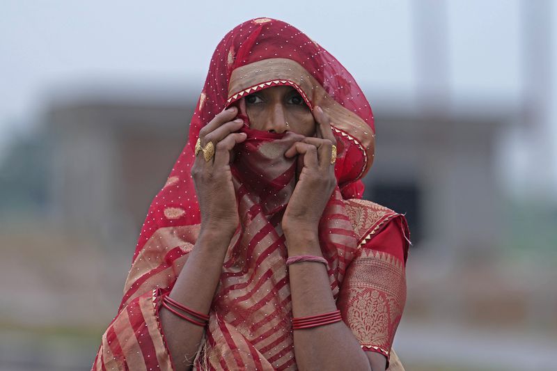 A woman watches members of a forensic team investigate the scene a day after a fatal stampede, in Fulrai village of Hathras district about 350 kilometers (220 miles) southwest of the state capital, Lucknow, India, Wednesday, July 3, 2024. Thousands of people at a religious gathering in India rushed to leave a makeshift tent, setting off a stampede Tuesday that killed at least 116 people and injured scores, officials said. (AP Photo/Rajesh Kumar Singh)