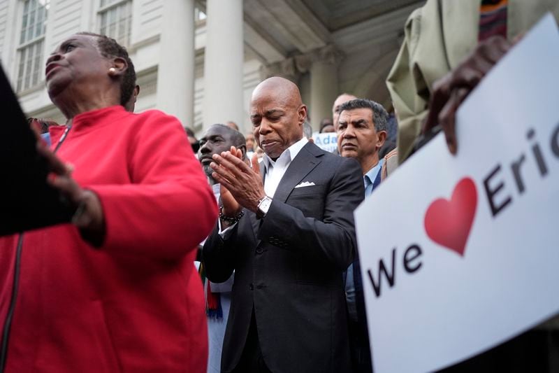 New York City Mayor Eric Adams, center, is surrounded by faith leaders and other supporters during a rally and prayer vigil on the steps of City Hall in New York, Tuesday, Oct. 1, 2024. (AP Photo/Seth Wenig)